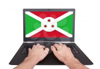 Hands working on laptop showing on the screen the flag of Burundi