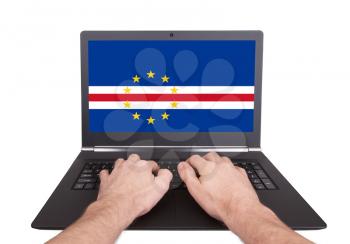 Hands working on laptop showing on the screen the flag of Cape Verde