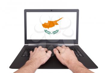 Hands working on laptop showing on the screen the flag of Cyprus