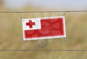 Border fence - Old plastic sign with a flag - Tonga