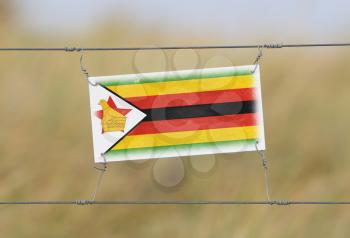 Border fence - Old plastic sign with a flag - Zimbabwe