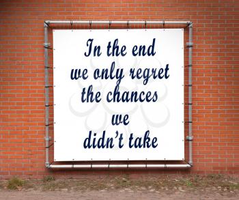 Large banner with inspirational quote on a brick wall - In the end we only regret the chances we didn't take