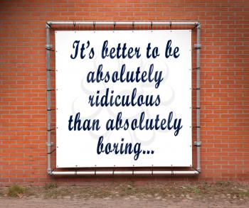 Large banner with inspirational quote on a brick wall - It's better to be absolutely ridiculous...