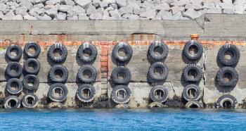 Old concrete mooring wall with car tires