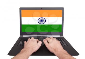 Hands working on laptop showing on the screen the flag of India