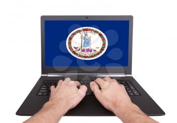 Hands working on laptop showing on the screen the flag of Virginia