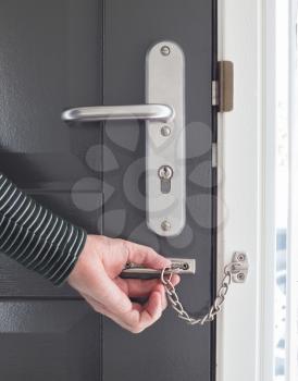 Door chain on a grey door, security measures
