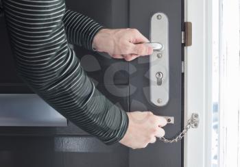Door chain on a grey door, security measures