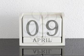 White block calendar present date 9 and month April on white wall background