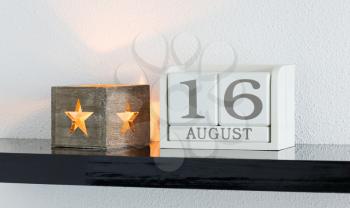 White block calendar present date 16 and month August on white wall background