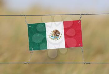 Border fence - Old plastic sign with a flag - Mexico