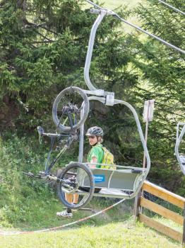 Nauders, Austria - August 4, 2017: Man with a mountainbike sitting in one of the many ski lifts in the Nauders area, summer sports.