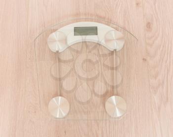 Glass weight scale standing on a wooden floor