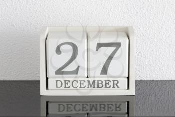 White block calendar present date 27 and month December on white wall background