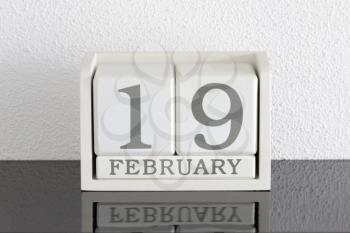 White block calendar present date 19 and month February on white wall background