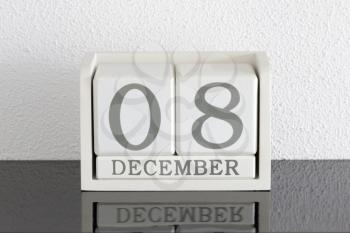 White block calendar present date 8 and month December on white wall background