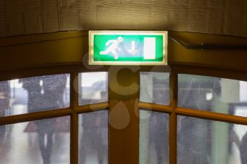 Green emergency exit sign hanging in an old building