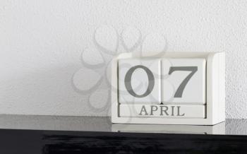 White block calendar present date 7 and month April on white wall background