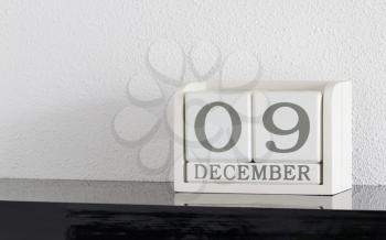 White block calendar present date 9 and month December on white wall background