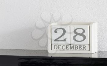 White block calendar present date 28 and month December on white wall background