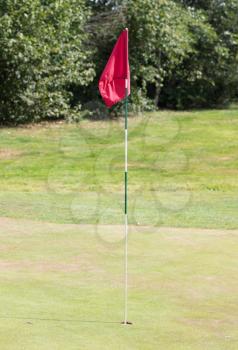 Red flag on a golf track, waving in the wind