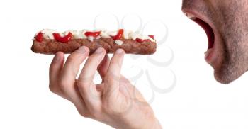 Man eating a frikadel with ketchup, mayonnaise on chopped onions, a Dutch fast food snack called 'frikadel speciaal'