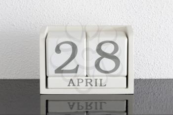 White block calendar present date 28 and month April on white wall background