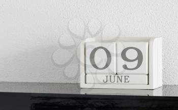 White block calendar present date 9 and month June on white wall background
