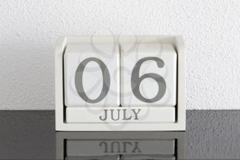 White block calendar present date 6 and month July on white wall background