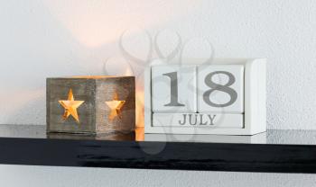 White block calendar present date 18 and month July on white wall background