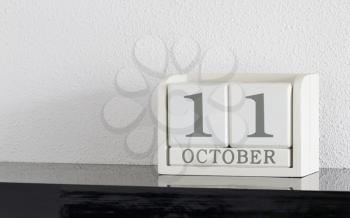 White block calendar present date 11 and month October on white wall background