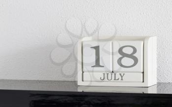 White block calendar present date 18 and month July on white wall background