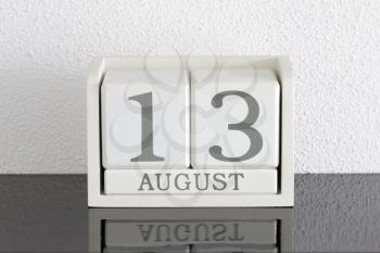 White block calendar present date 13 and month August on white wall background
