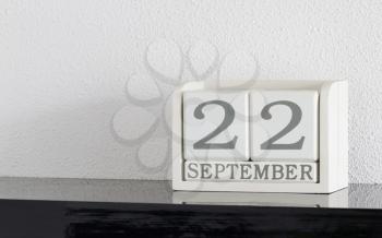 White block calendar present date 22 and month September on white wall background