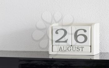 White block calendar present date 26 and month August on white wall background