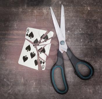 Concept of addiction, card with scissors, eight of spades