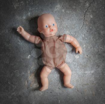 Abandoned doll laying on a concrete floor