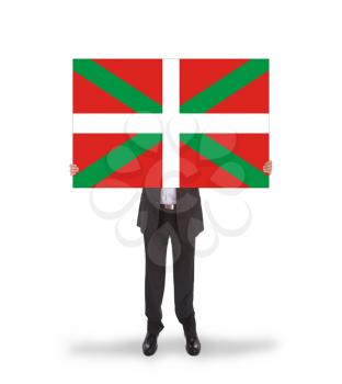 Smiling businessman holding a big card, flag of Basque Country, isolated on white