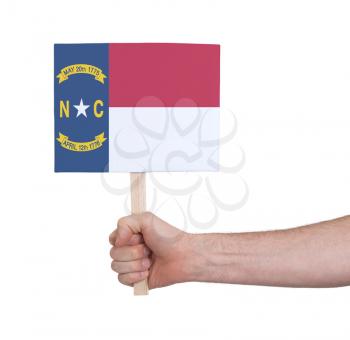Hand holding small card, isolated on white - Flag of North Carolina