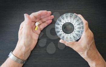 Elderly person taking medication, two different pills