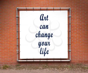Large banner with inspirational quote on a brick wall - Art can change your life