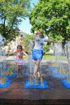 little sympathetic girl with her mother playing in fountains
