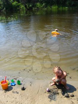 children are playing on the sand at the river and swimming