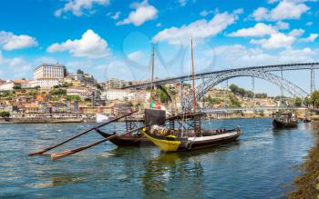 Traditional boats with wine barrels and Douro River in Porto in a beautiful summer day, Portugal