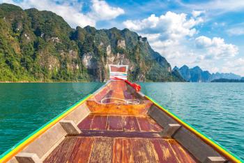 Wooden thai traditional long tail boat on Cheow Lan lake, Ratchaprapha Dam, Khao Sok National Park in Thailand in a summer day