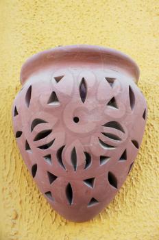 Clay oriental brown lamp on yellow decorative stucco wall.