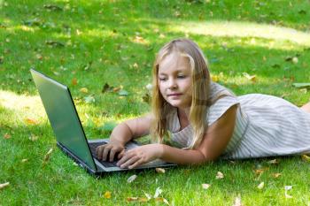 Image of cute girl with laptop on green grass