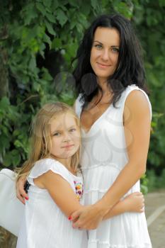 Brunette mother and blond daughter in white