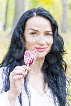 Caucasian brunette woman eating red candy with long hairs