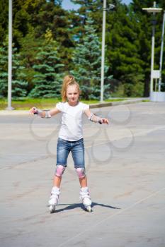 Learning girl on roller skates in summer
